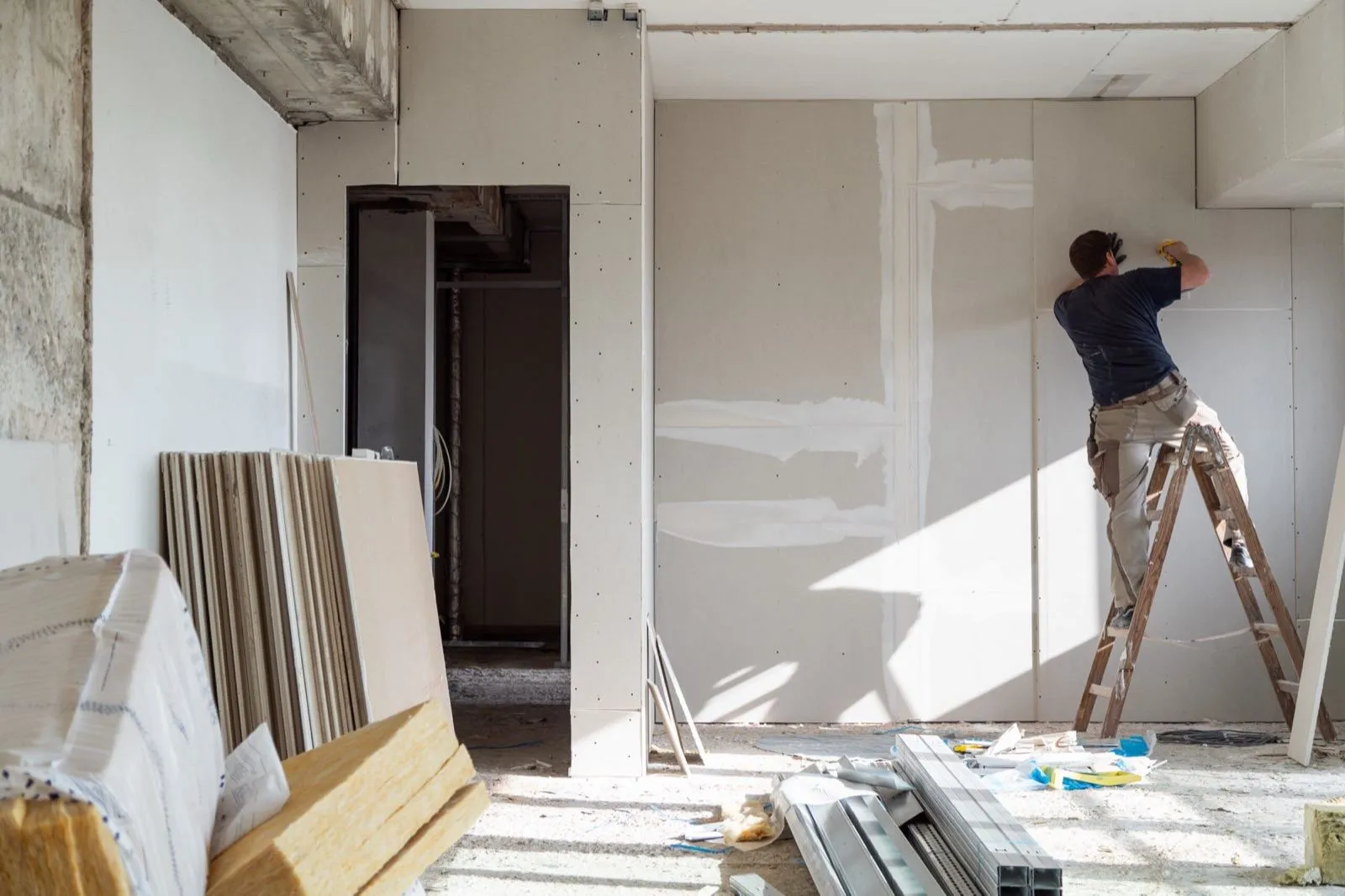Vakman aan het werk aan een binnenwand tijdens een renovatie — rustige, persoonlijke werkwijze