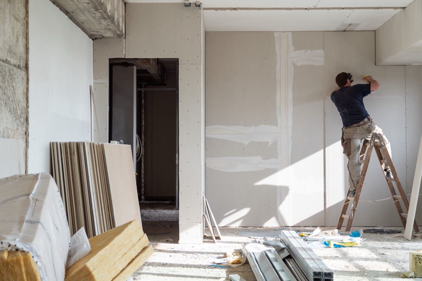 Vakman aan het werk aan een binnenwand tijdens een renovatie — rustige, persoonlijke werkwijze